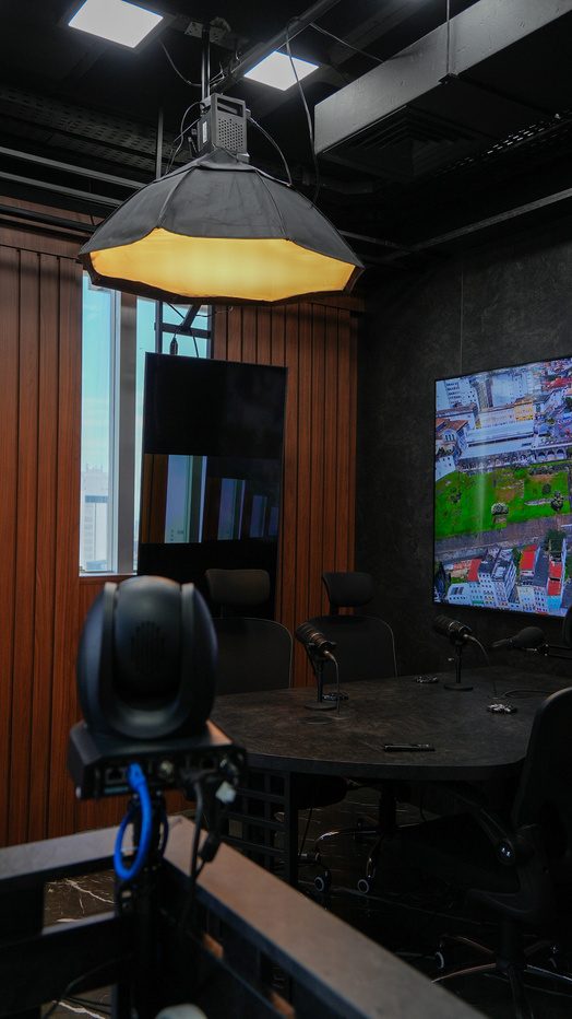 Mesa de gravação do estúdio com painel de madeira e telas exibindo cenário